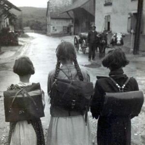Trois écolières, de dos, regardent la rue de l'école.